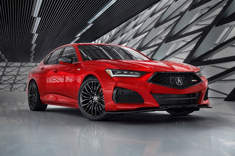 Red Acura sedan displayed indoors against a modern geometric wall