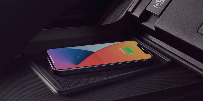 Smartphone placed on the wireless charging pad in the center console of an Acura SUV