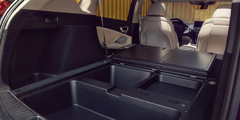 Rear cargo area of an Acura SUV showing an underfloor storage compartment with multiple storage sections