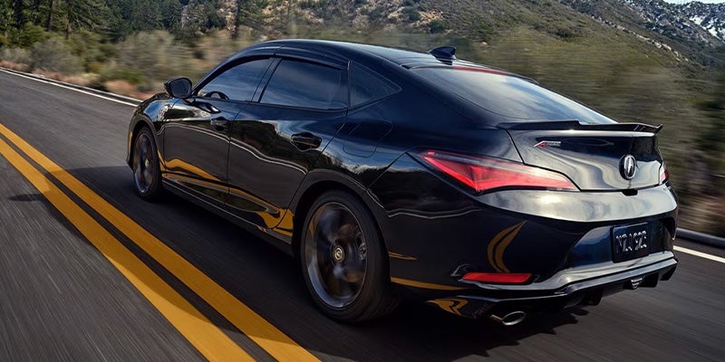 Black Acura sport sedan driving on a winding mountain road, shown from a rear three-quarter