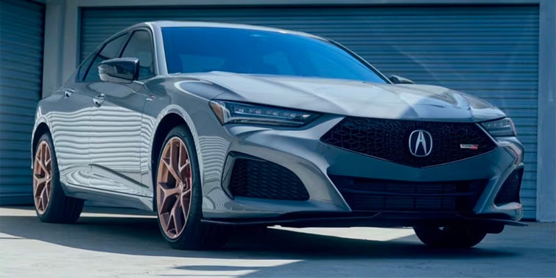 Gray Acura sedan parked outdoors in front of industrial-style garage doors