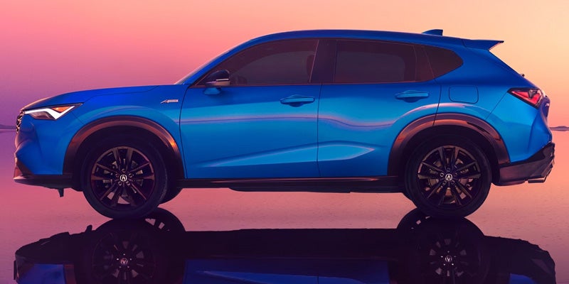 Blue Acura SUV driving through a desert roadway.