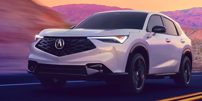 Rear view of a white Acura SUV driving on a road