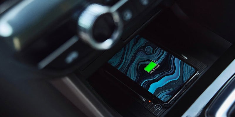 Smartphone placed on a wireless charging pad in the center console of an Acura vehicle