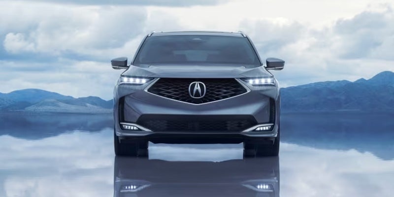 Front view of a gray Acura SUV positioned on a reflective surface
