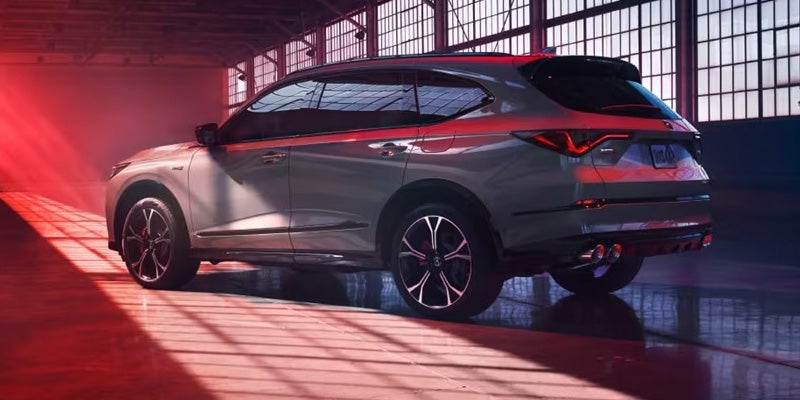 Gray Acura SUV parked in a large industrial space with dramatic red lighting